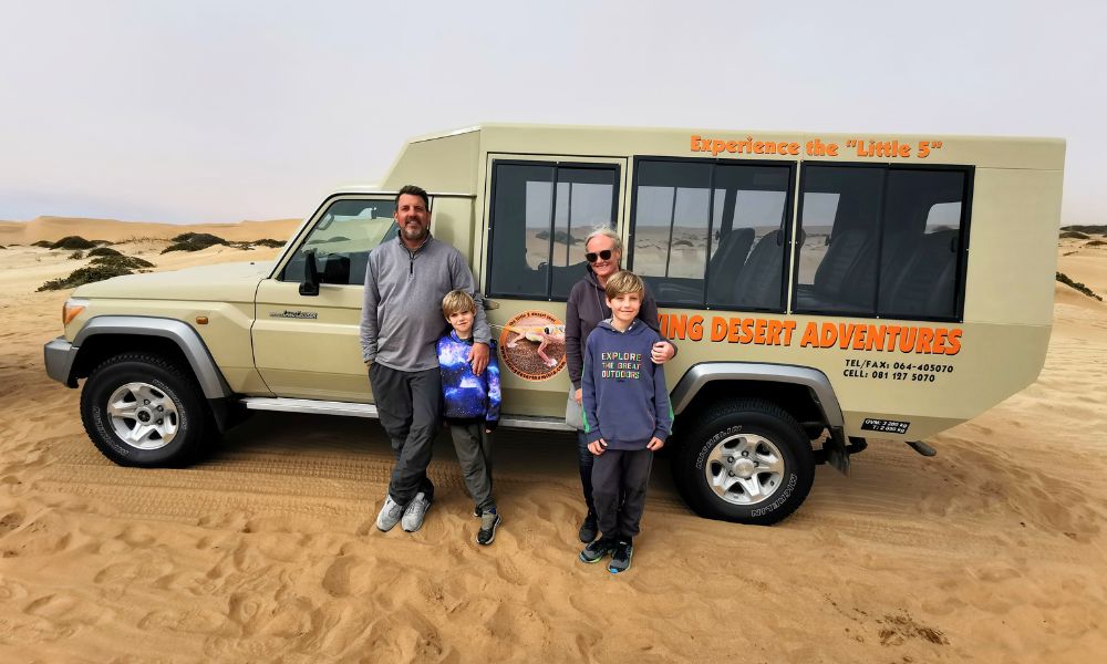 Family of four standing in front of a Living Desert Adventures safari jeep on one of the best tours in Swakopmund.