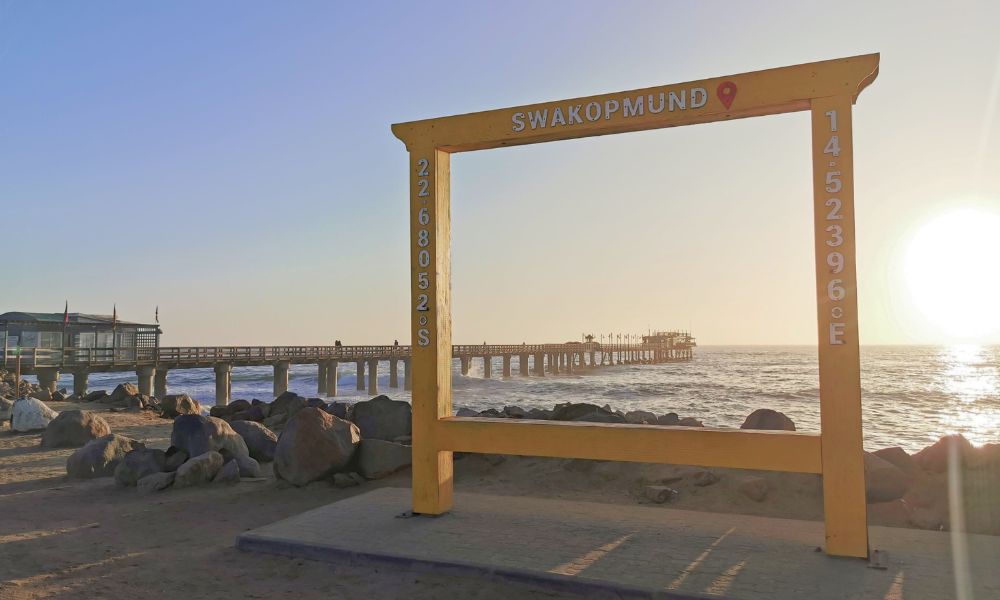 Large yellow frame in Swakopmund with Swakopmund pier in the background at sunset.