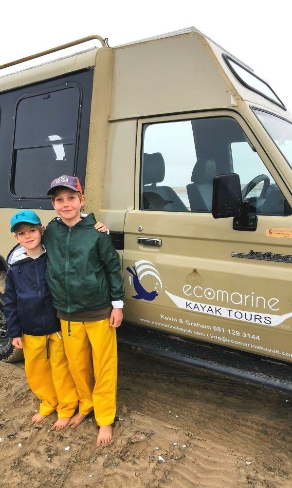 Two young boys in waterproofs standing by an Ecomarine Kayak tour jeep.