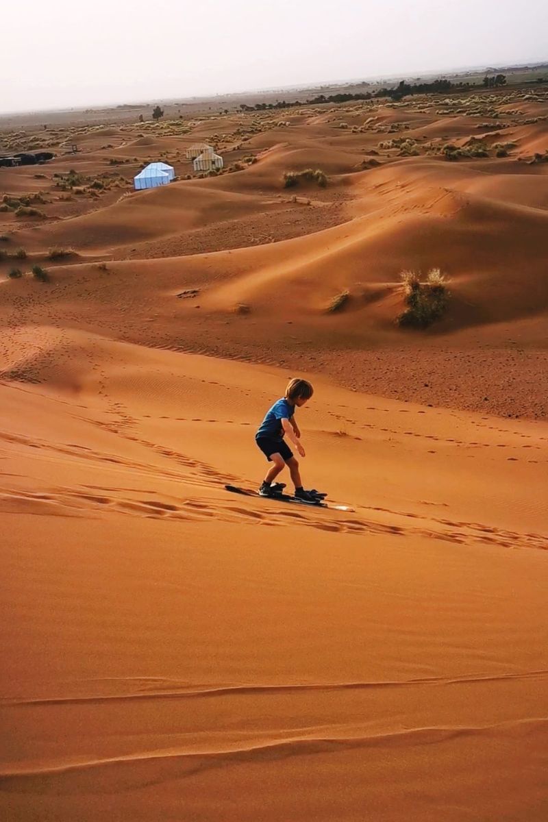 Child sandboarding in Zagora at Tinfou Desert Camp in Morocco.