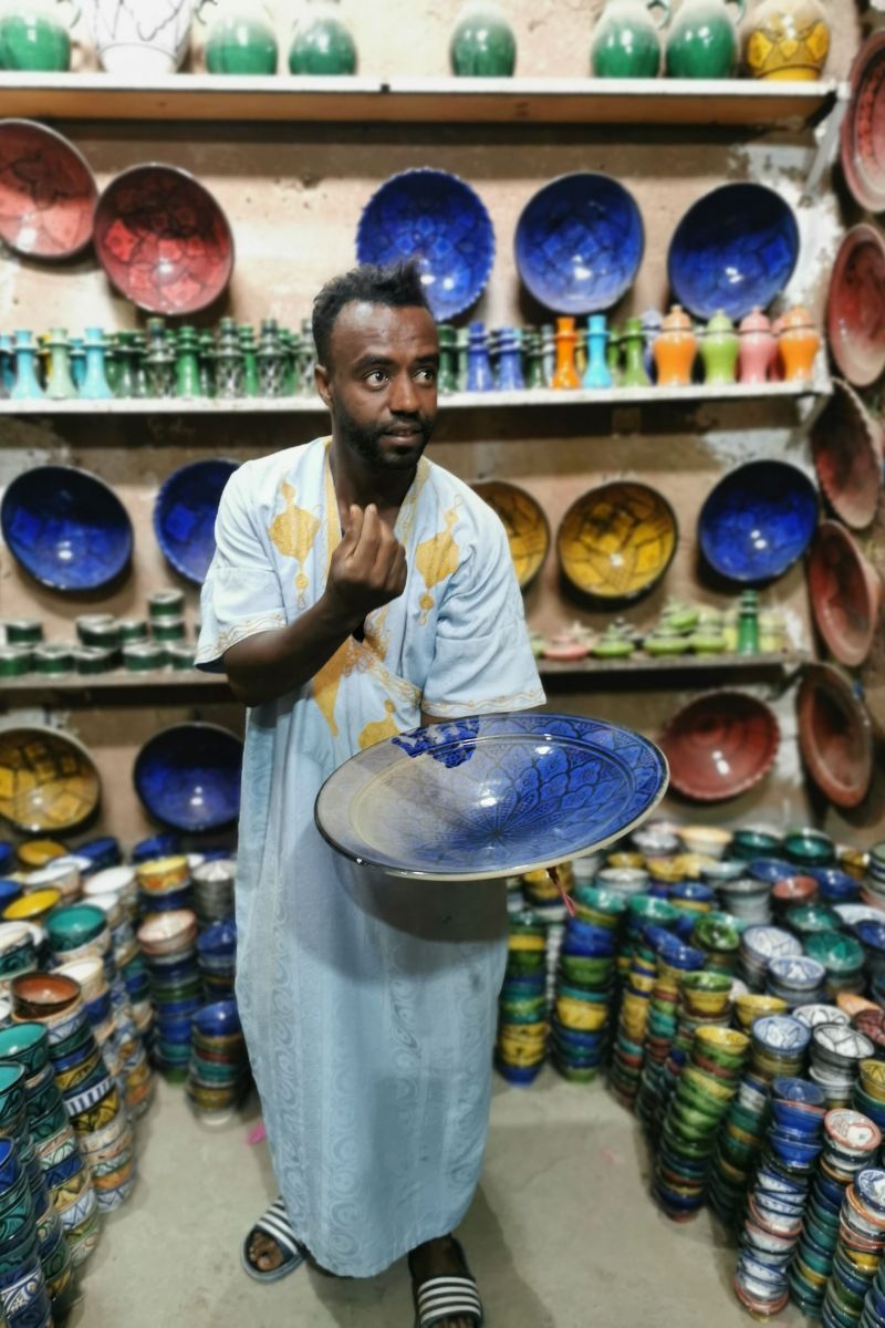 Man holding a large blue Moroccan platter in the pottery co-operative in Tamegroute near Zagora.