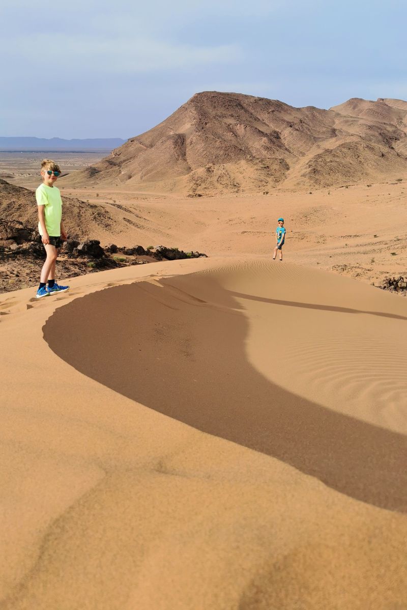 Kids walking up the sand dunes at Jebel Zagora in Morocco during a 7 day Morocco road trip..